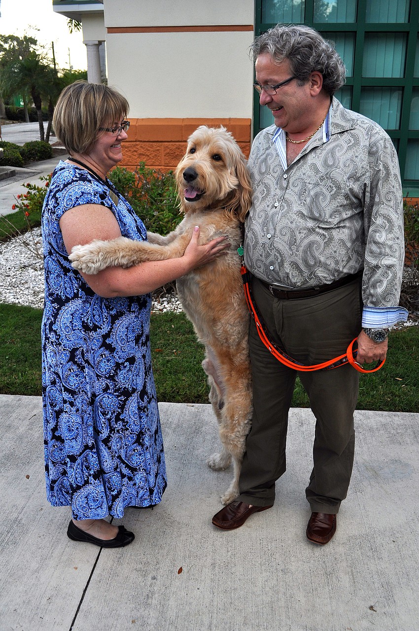 Morgan Gerhart dances with Dudley as Adam Chicoine looks on, Thursday, March 15, at Yappy Hour.