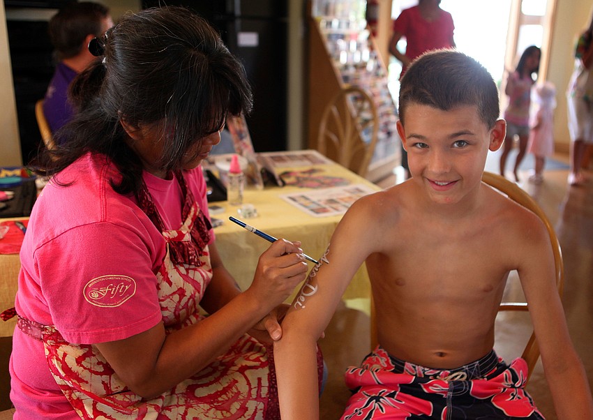 Akiko Campbell writes out a saying on Jonathan Andersonâ€™s, 11, arm, Thursday, April 5, at Siesta Dunesâ€™ egg hunt.