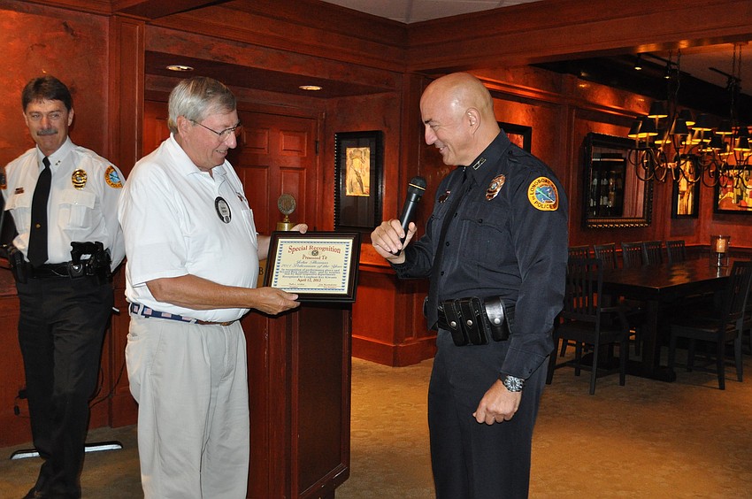 John Wild presents a certificate of appreciation to Officer John Thomas