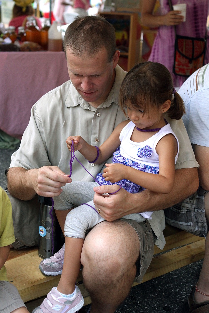 Joe Cacka and Anabel Procel-Cacka, 3, do some finger chaining at the Knit-a-thon at the Waldorf Schoolâ€™s tent.