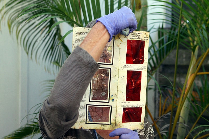 Jane Boyd looks through a value filter composition guide before continuing on with her painting, Thursday, Jan. 12, in Towles Court with the rest of the Plein Air Sun Coast artists.