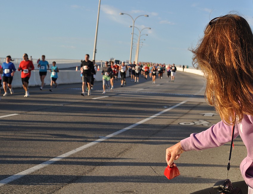 Susan Hammond cheers runners along with a bell.