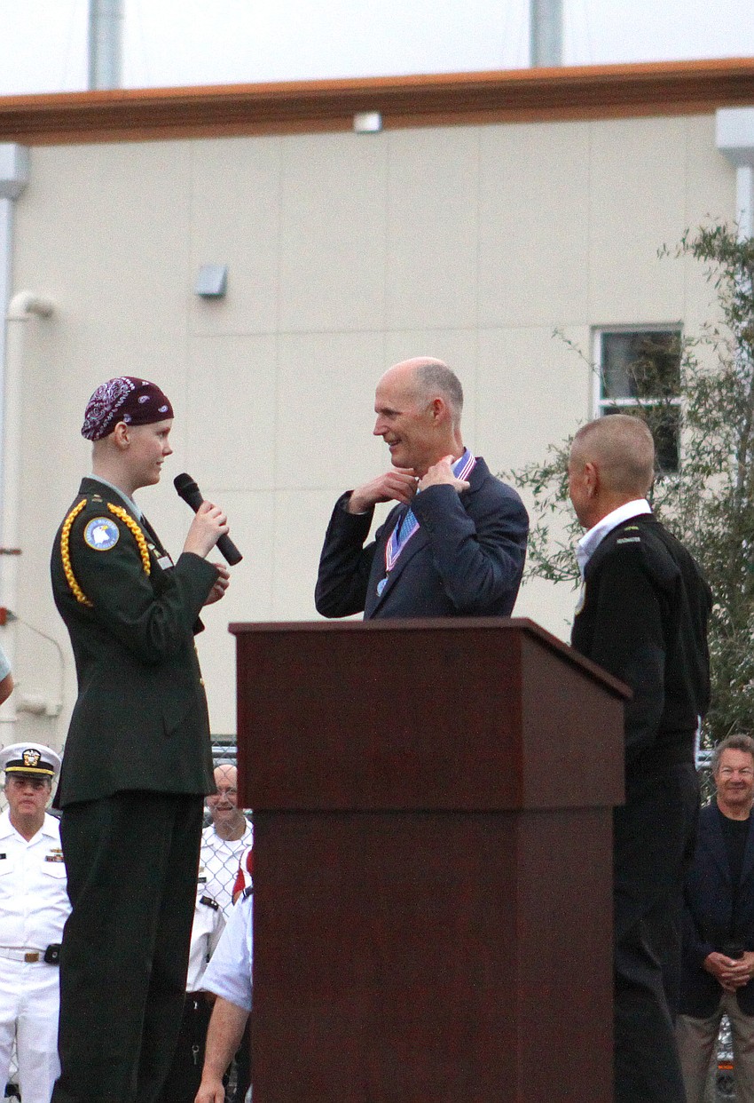 Ashley Krueger, junior, gives Gov. Rick Scott a medallion with Sarasota Military Academy's school crest, Friday, Feb. 17, during his visit to Sarasota Military Academy.