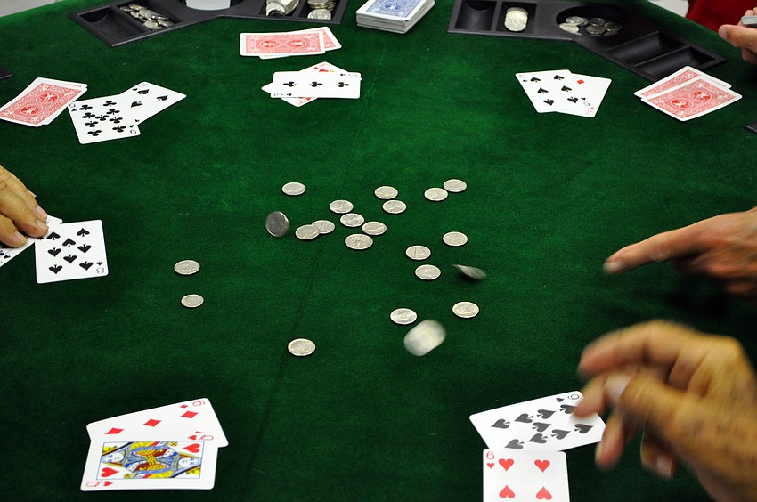 The men throw dimes and nickels in the center of the table.