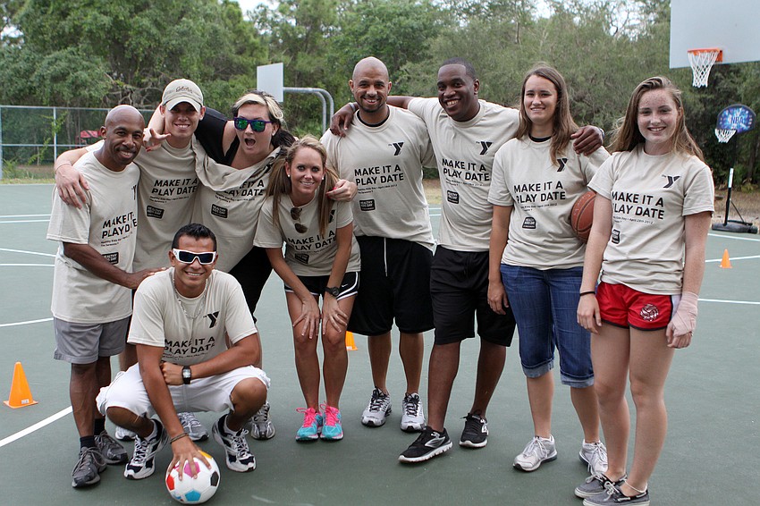 YMCA staff members pose together by the football, soccer and basketball obstacle courses that were set up for Healthy Kids Day.