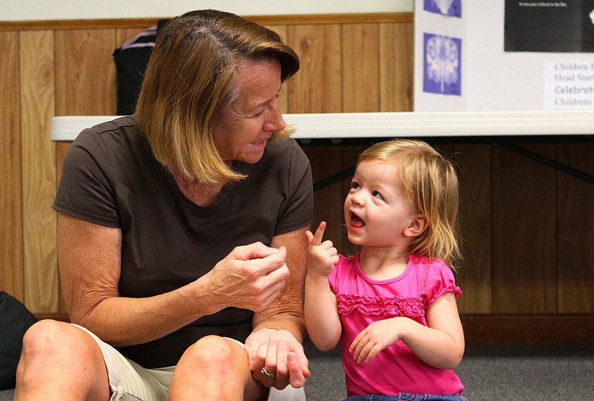 Kathy Peters smiles as Brooklyn Peters, 21 mos., does the sign for â€œcandleâ€.