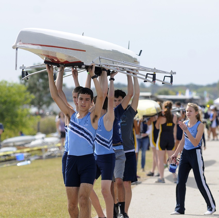 Members of St. Johnâ€™s Country Day Schoolâ€™s rowing team carry their boat up to launch dock.