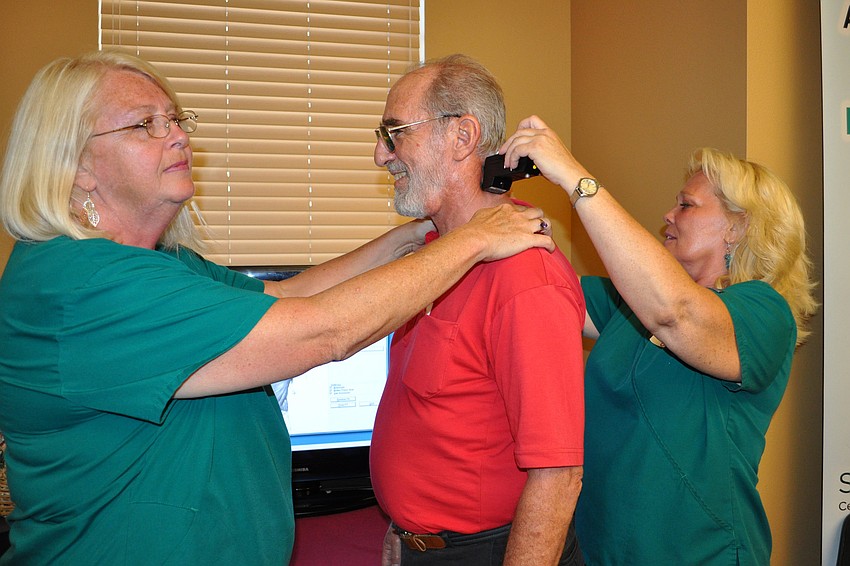 Linda Delgado, left, and Janet Rifkin, right, did a spinal screening on Mark Walzer.