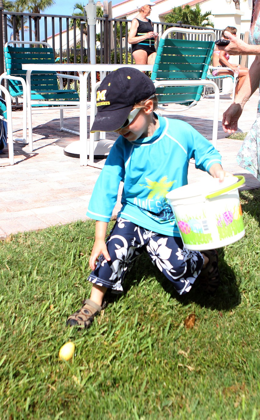 Ethan Schmit, 4 Â½, finds a yellow egg in the grass much to his delight.