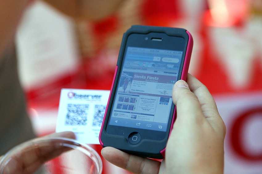 Gabriele Vest tries to win the Observerâ€™s margarita gift basket by scanning a QR code card, Thursday, April 12, at the Hob Nob at Phillippi Estate Park.