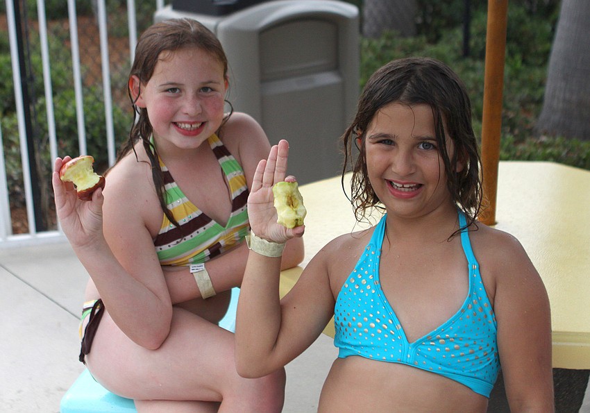 Sierra Sibley, 8, and Mia Merring, 8, enjoy their apples by the pool, Friday, April 20, during the YMCA Healthy Kids Day event.