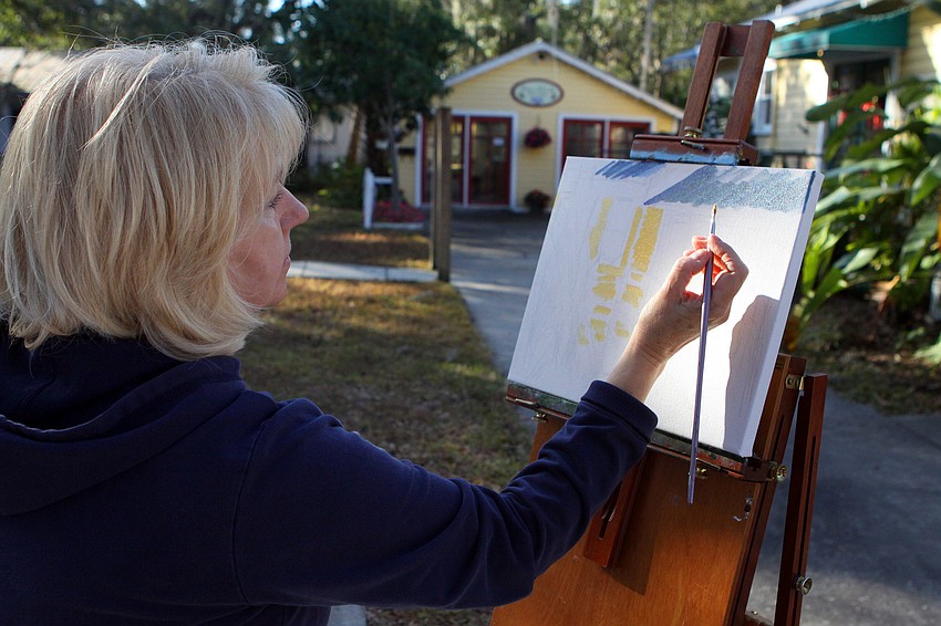 Mary Ann Ellicott, of Venice, paints a yellow building, Thursday, Jan. 12, in Towles Court.
