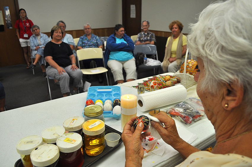 Tetiana Silecky wipes off the excess bees wax from her egg at the end of her demonstration at the Gulf Gate Library on Tuesday.