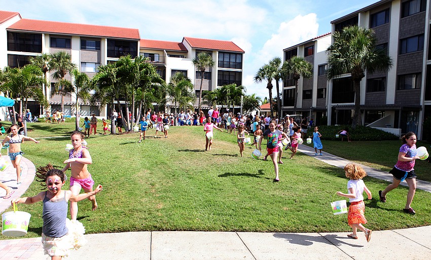 Kids begin running around the lawn by the pool at Siesta Dunes looking for eggs in the grass, bushes and trees.