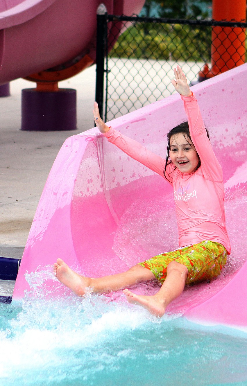 Erica Daphin, 7, raises her arms up in the air as she makes her way down the water slide, Friday, April 20, during Healthy Kids Day.