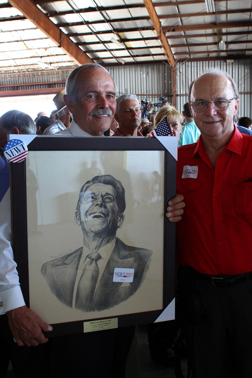 Robert Barron holds up a drawing of Ronald Reagan done by Art Terry, right, during the Newt Gingrich rally on Tuesday. Barron ended up giving the rare collection piece to Gingrich as he got back on the bus.