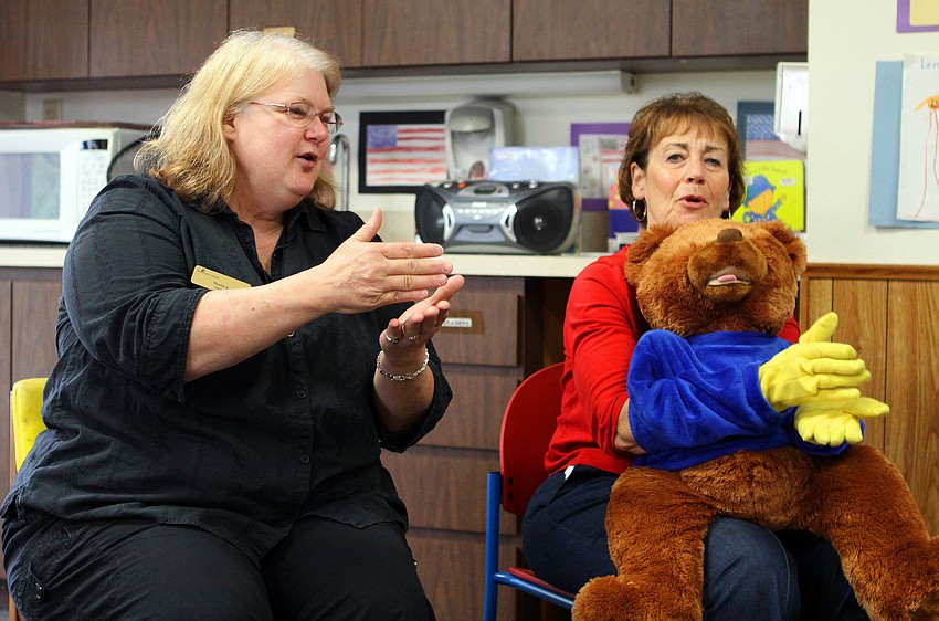 Nancy Velazquez, Janice Frankel and BeeBo show the children, parents and caregivers the sign for â€œcakeâ€.