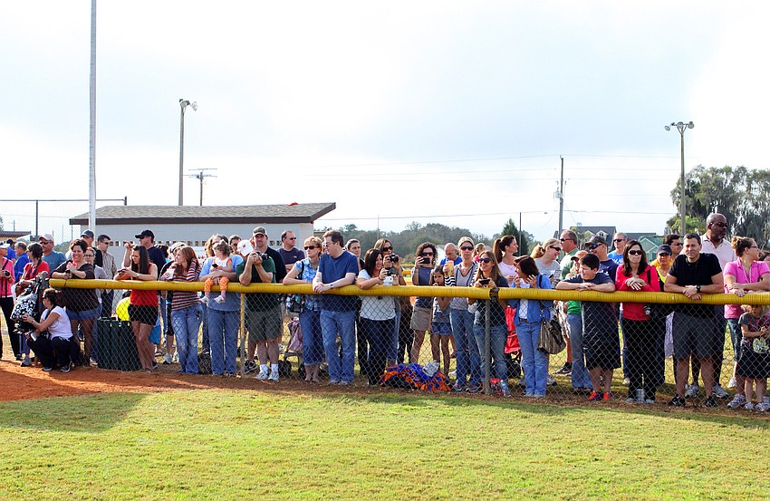 Parents and siblings wait outside the gate surrounding field one, Saturday, Feb. 18, during the opening day ceremony for Sarasota Little League.