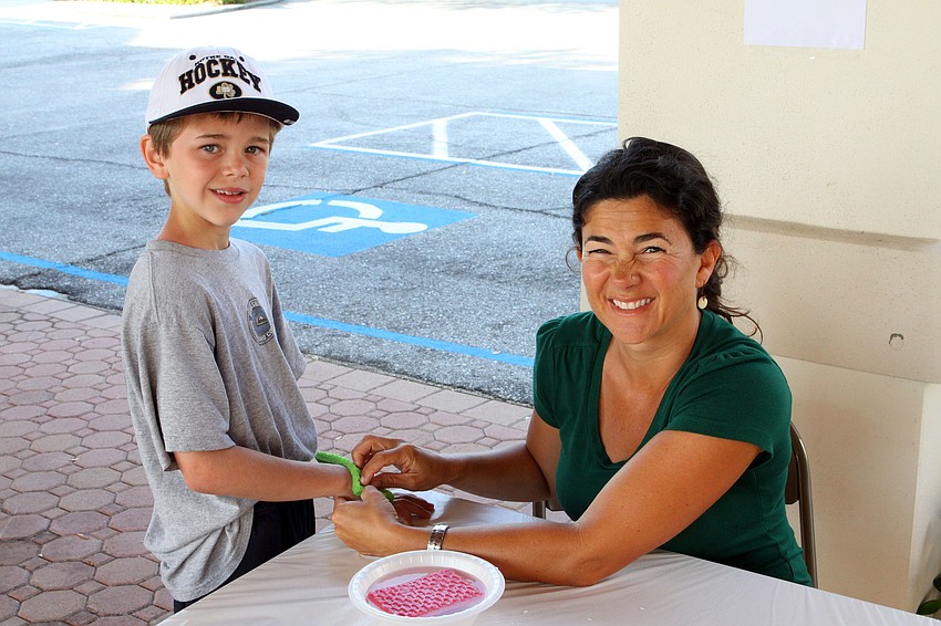 Reece Rochester, 9, gets a temporary tattoo from Suzanne Koscho.