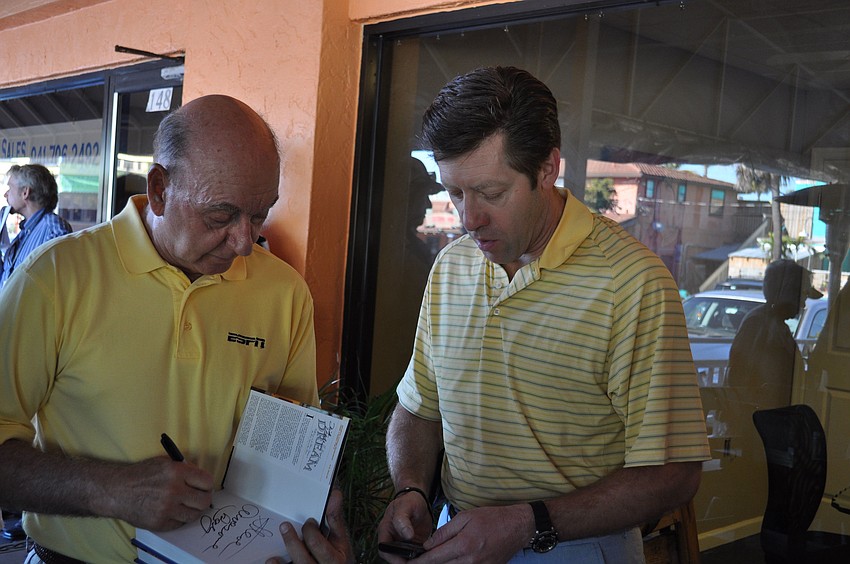 Dick Vitale autographs one of his books for Steve Stevens.