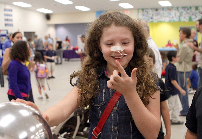 Nicole Jolly, 9, has fun trying to touch a piece of string stuck to her nose while holding on to the Van de Graaff generator.