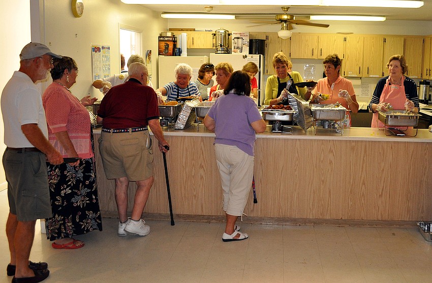 People line up to fill their plates with flounder, hushpuppies and coleslaw from Walt's Fish Market, Friday, March 23, at St. Michael the Archangel.