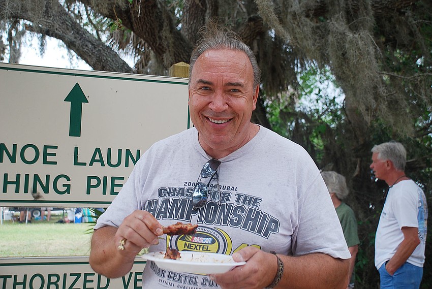 John Kravis stays dry from the rain while he eats his ribs