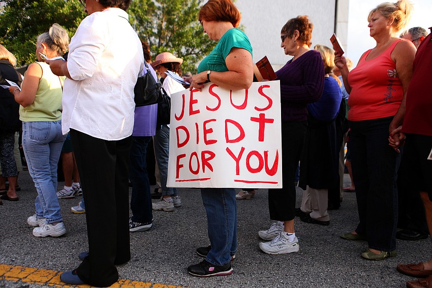 A woman holds a homemade sign that read â€œJesus Died For Youâ€ during the Stations of the Cross walk on Good Friday.