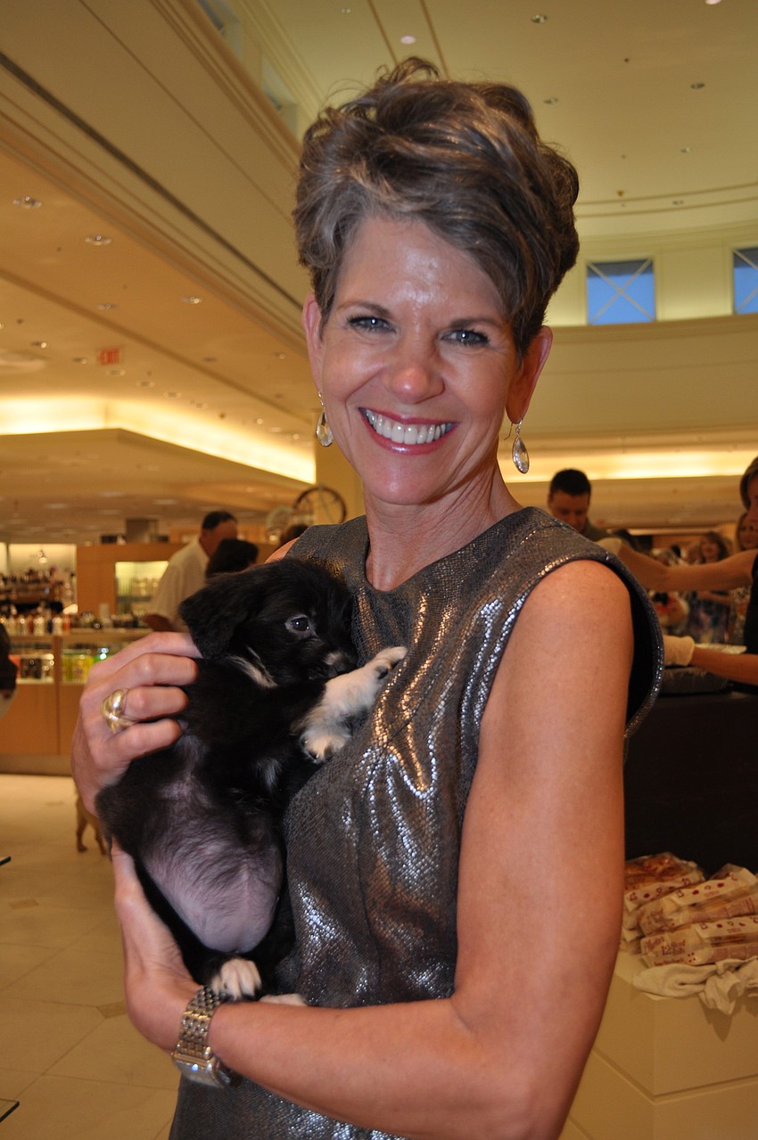 Sally Schule holds a puppy up for adoption.
