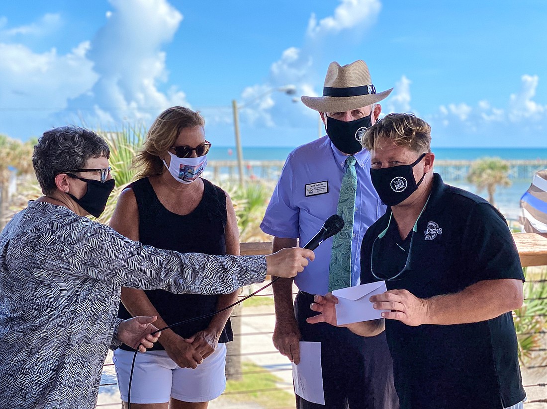 Flagler County PIO Julie Murphy holds the microphone for Tortugas owner Scott Fox, with Flagler Beach Mayor Linda Provencher and Flagler County Commission Chairman Dave Sullivan. Courtesy photo