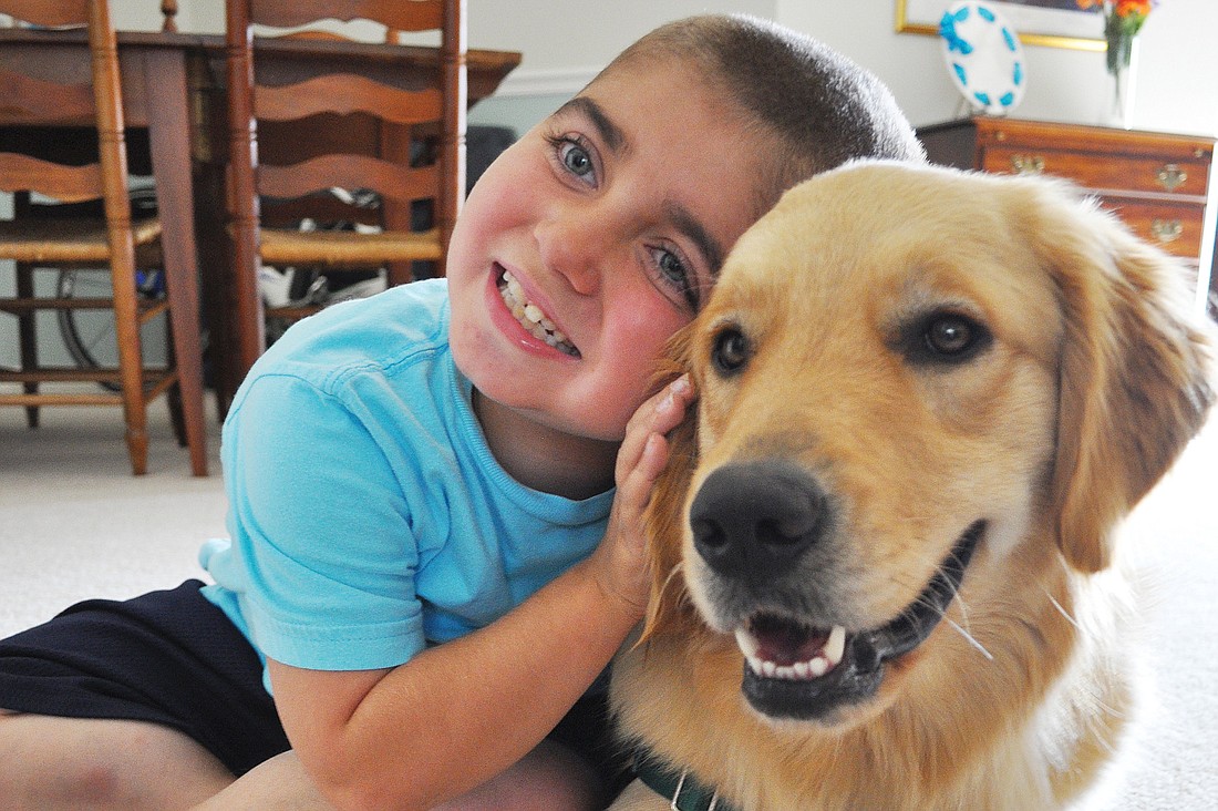 Grayson Tullio, 8, is excited to have his own service dog, Hooch, at home with him.