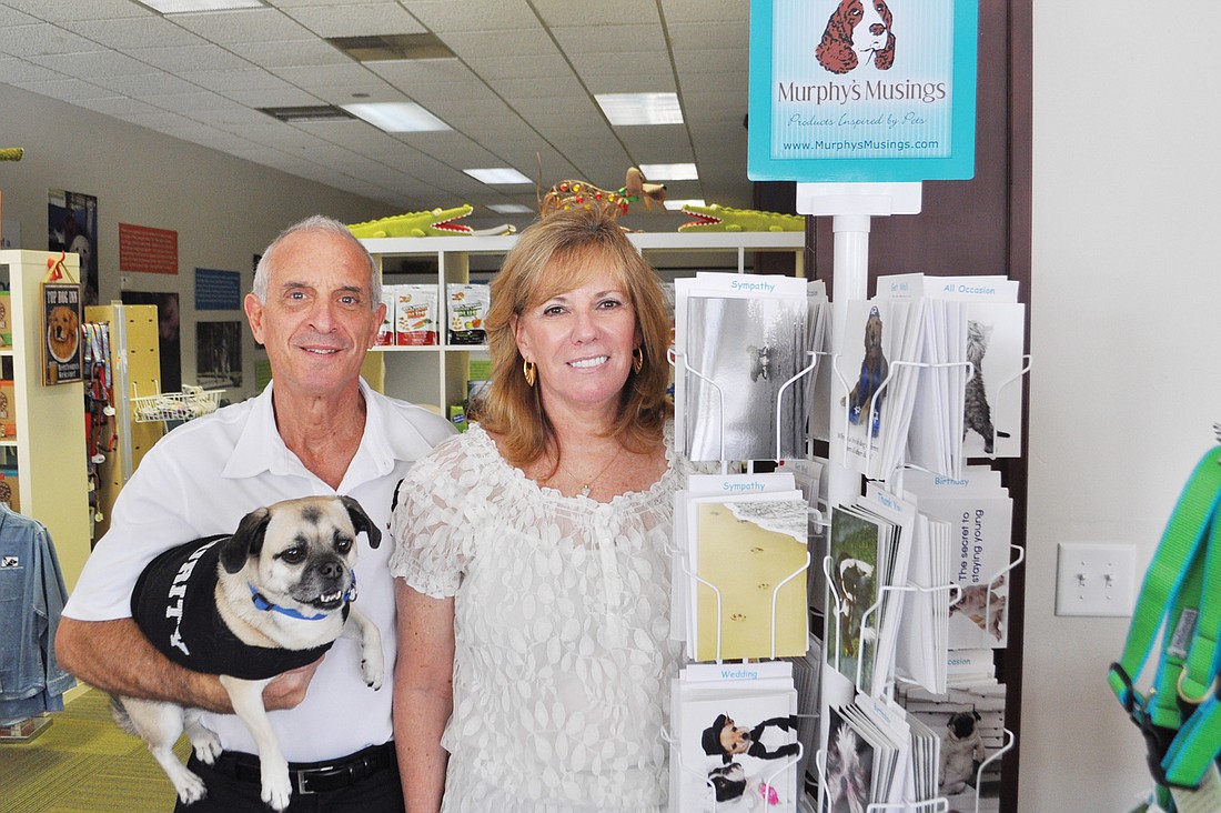 Steve and Anne Udell pose by their card rack at Southeastern Guide Dogs with their dog, Schmutzie.