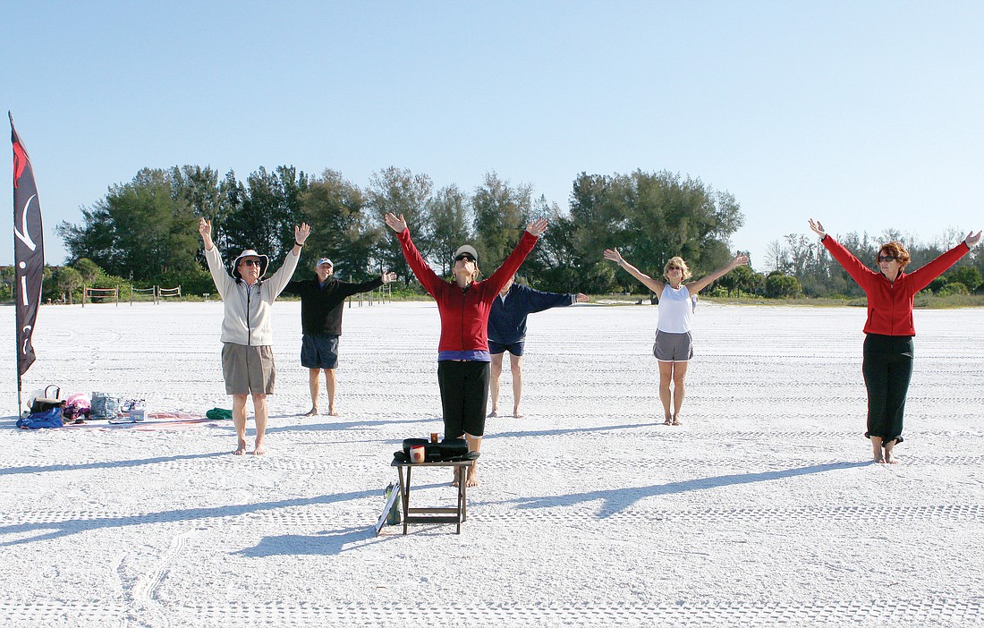 Kathy Oravec leads the group in reaching up high during the beginning of her NIA class, Tuesday, April 24, on Siesta Key Public Beach.