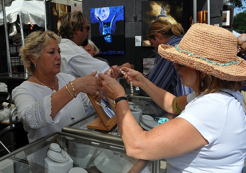 Marcy Johannes prepares to wrap up a necklace bought by Valerie Cox from Raven Wood Studios, Saturday, May 19.