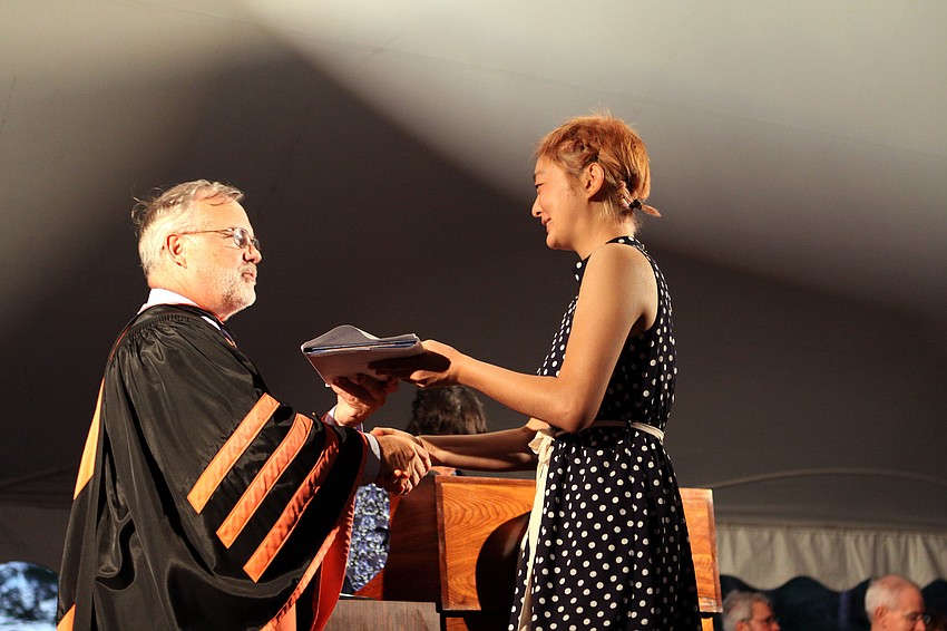 Joohyn Kim receives her diploma, Friday, May 25, from President Michalson of New College.