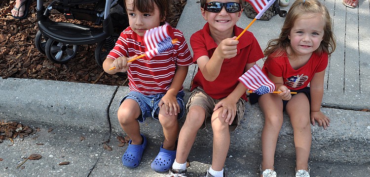 Dominic Stratford, 3, Aiden Baker, 4, and Ava Baker, 2, wave their flags during the parade.
