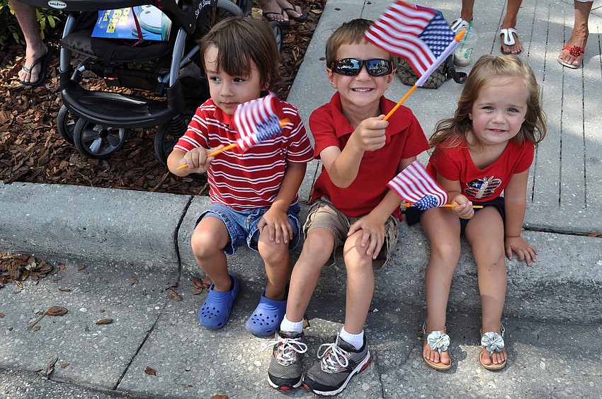 Dominic Stratford, 3, Aiden Baker, 4, and Ava Baker, 2, wave their flags during the parade.