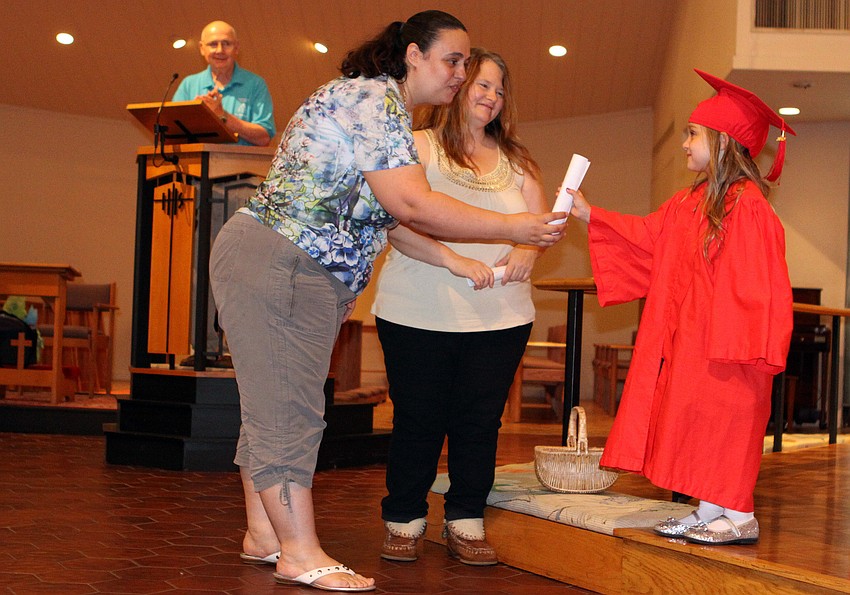 Violet Walsh, 5, receives her diploma from her teachers Connie Graham and Kat Wors as Dick Aubry looks on, Friday, June 1, at St. Boniface.