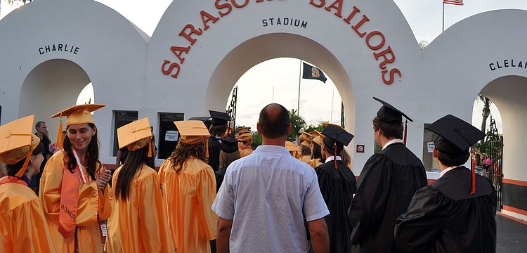 The boysâ€™ and girlsâ€™ lines merged as the graduates headed out onto the football field.