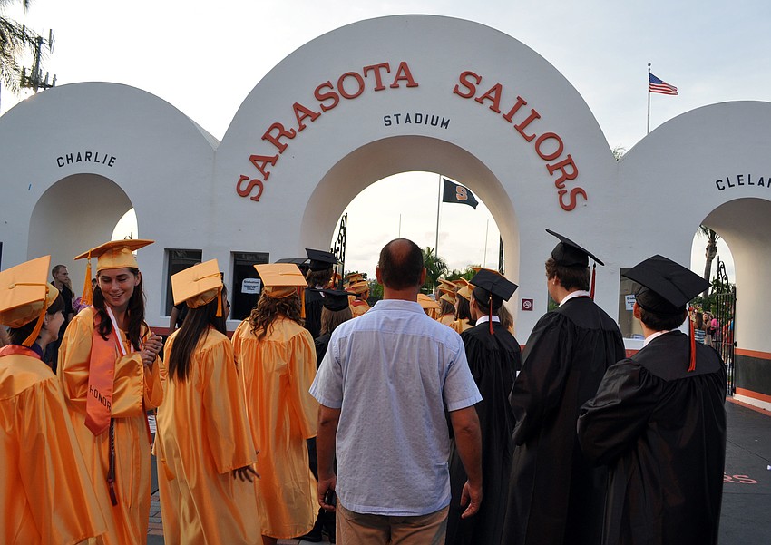 The boysâ€™ and girlsâ€™ lines merged as the graduates headed out onto the football field.