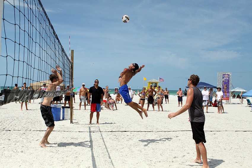 Roger Corvitt jumps up to spike the ball while Garrett Rasmussen prepares himself and Stefan Meyer looks on.