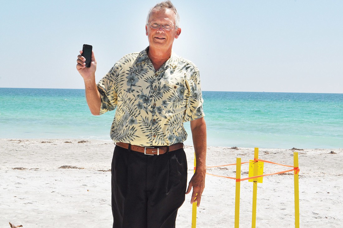 Jim Holbrook uses his app BeachWalk1.0. during a walk on a Longboat Key beach.