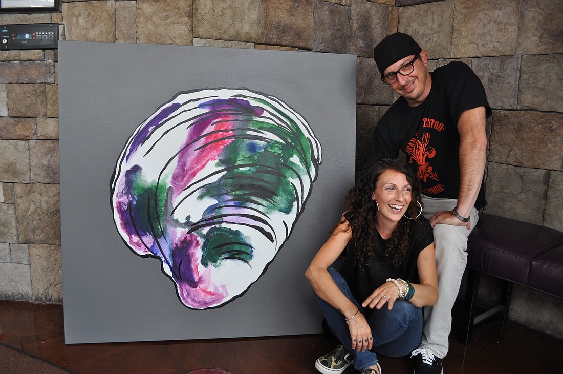 Phallen Coyne and Matt Foley with one of several shellfish paintings Coyne created for her family's new Sarasota restaurant.