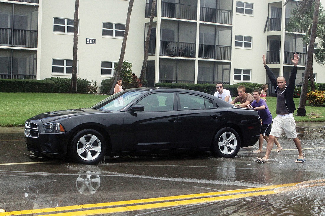 Five men push a vehicle Monday through the Beach Road intersection in front of the main access to Siesta Key Beach.