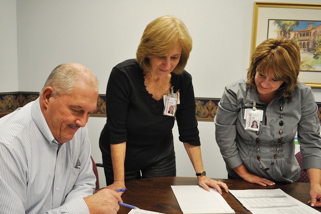 Manatee County Financial Management Director Jim Seuffert reviews budget documents with co-budget division managers Angie Bibler and Jan Brewer.