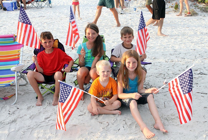 In chairs, Nick Gray, 8, Ashlyn Weaver, 10, and Joshua Gray, 4, on ground, William Willard, 4, and Kayla Willard, 9, wave their American flags, Wednesday, July 4.