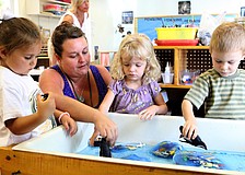 Ari Benson, Lauren Schuth, Davina Chait and Hendrix Nunnery play at the water table with plastic penguins and blocks of ice filled with plastic fish, Monday, July 16, during Penguins Aplenty, Penguins Galore camp at Forty Carrots.