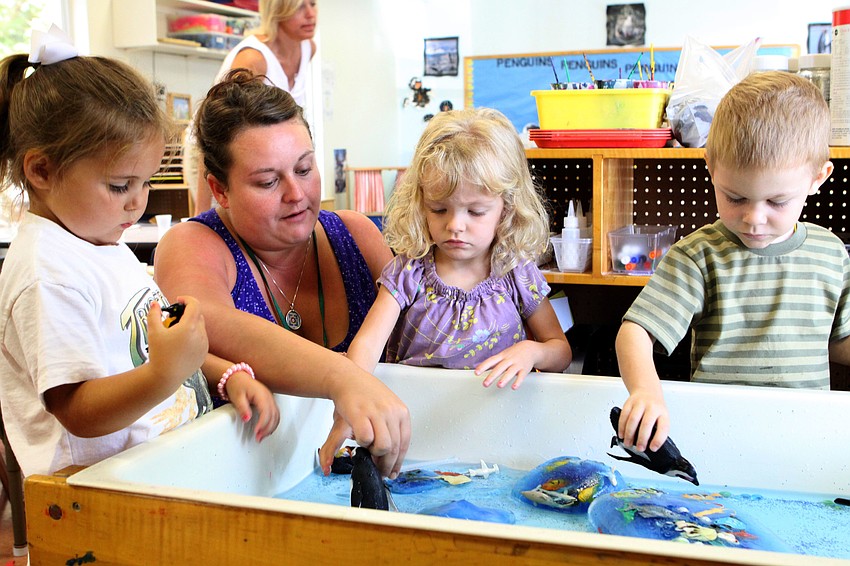 Ari Benson, Lauren Schuth, Davina Chait and Hendrix Nunnery play at the water table with plastic penguins and blocks of ice filled with plastic fish, Monday, July 16, during Penguins Aplenty, Penguins Galore camp at Forty Carrots.