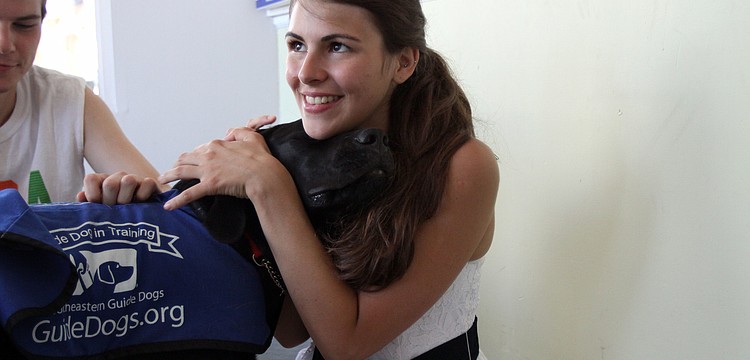 Doc snuggles up to Beatriz Urrutia, Saturday, July 21, in the playing and petting area during Puppy Love at Southeastern Guide Dogs Sarasota.