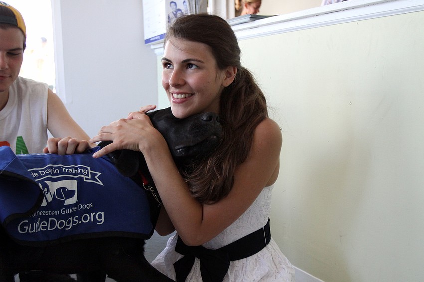Doc snuggles up to Beatriz Urrutia, Saturday, July 21, in the playing and petting area during Puppy Love at Southeastern Guide Dogs Sarasota.